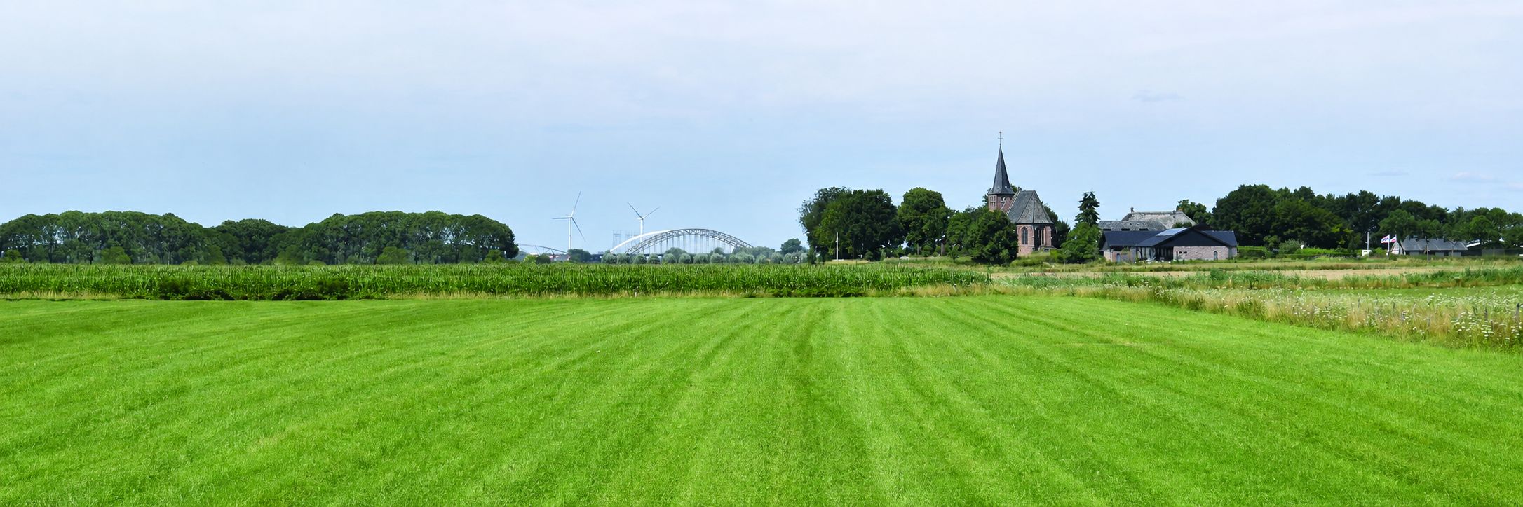 Het kerkje van Persingen in het landschap van de Ooijpolder, gezien vanaf de weilanden