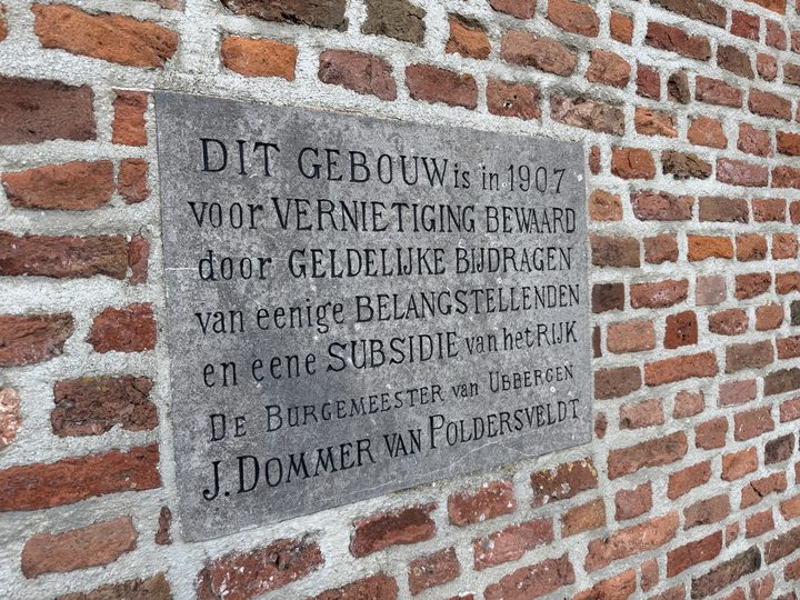 De gedenksteen aan de toren, geplaatst door burgemeester J. Dommer van Poldersveldt bij de redding van het kerkje in 1907